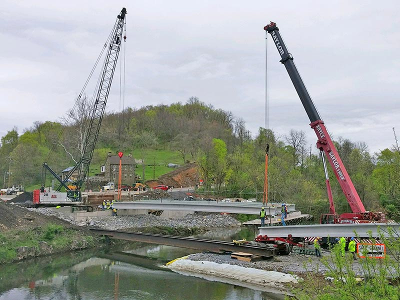 Cranes lifting concrete beams into place for bridge construction